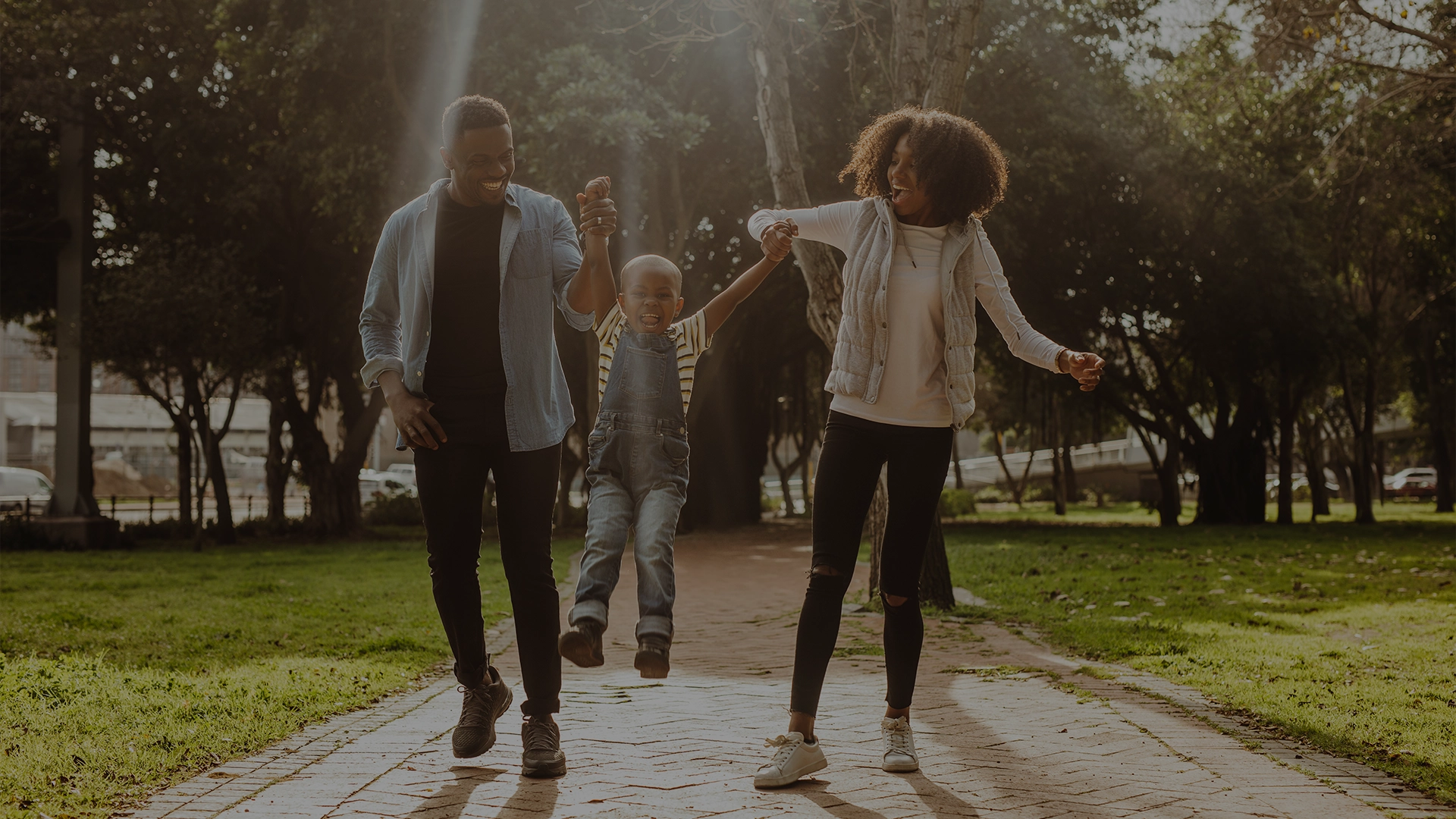 Family with child jumping between them at Keystone Creek Calgary